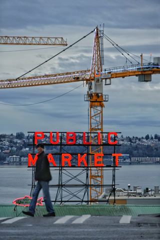 The Public Market sign in Seattle seen against a construction crane and Elliott Bay on a grey day
