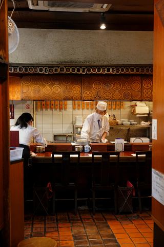 A chef at work behind a small sushi counter in Tokyo
